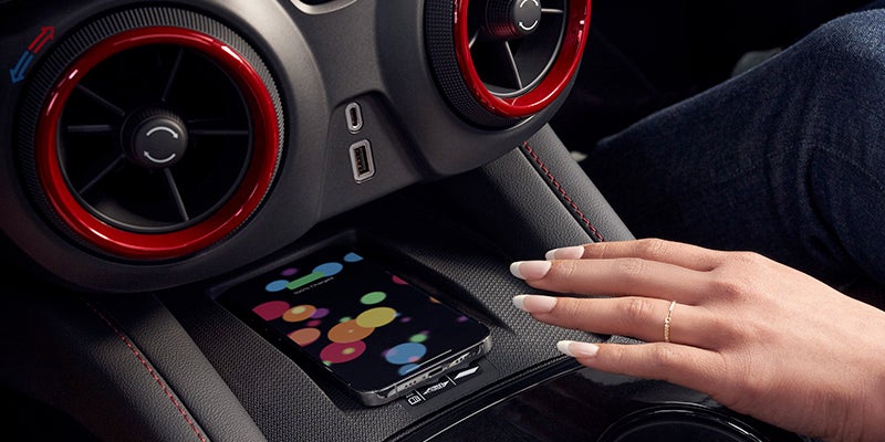 A woman's hand rests on the steering wheel of a car, indicating she is in the driver's seat.