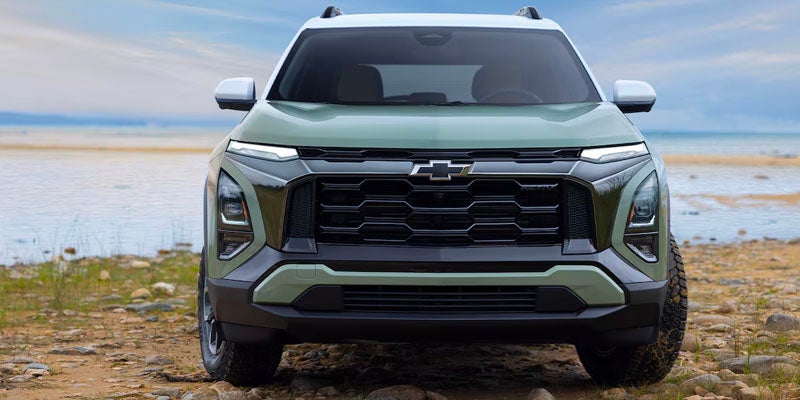 A 2025 Chevrolet Equinox parked on the sandy beach with waves gently lapping at the shore in the background.