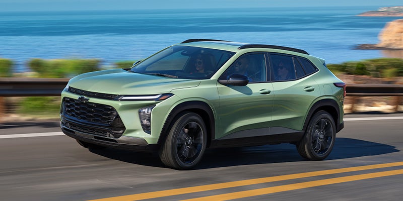 A 2025 Chevrolet Trax driving down a road, showcasing its sleek design and modern features.