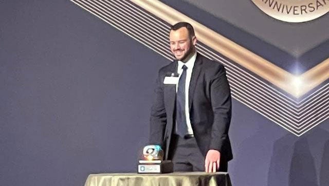 A man in a suit stands on stage