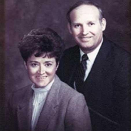 A man and woman in business attire smiling and posing together for a professional photo.