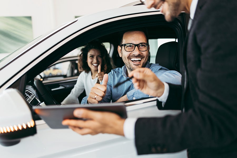 A smiling man and woman in a car, enjoying a moment together.